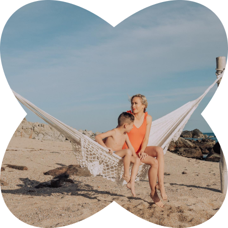 Kam and son relaxing in white hammock on sandy beach with ocean view