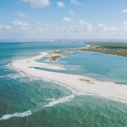 Aerial view of curved white sand island surrounded by turquoise ocean water
