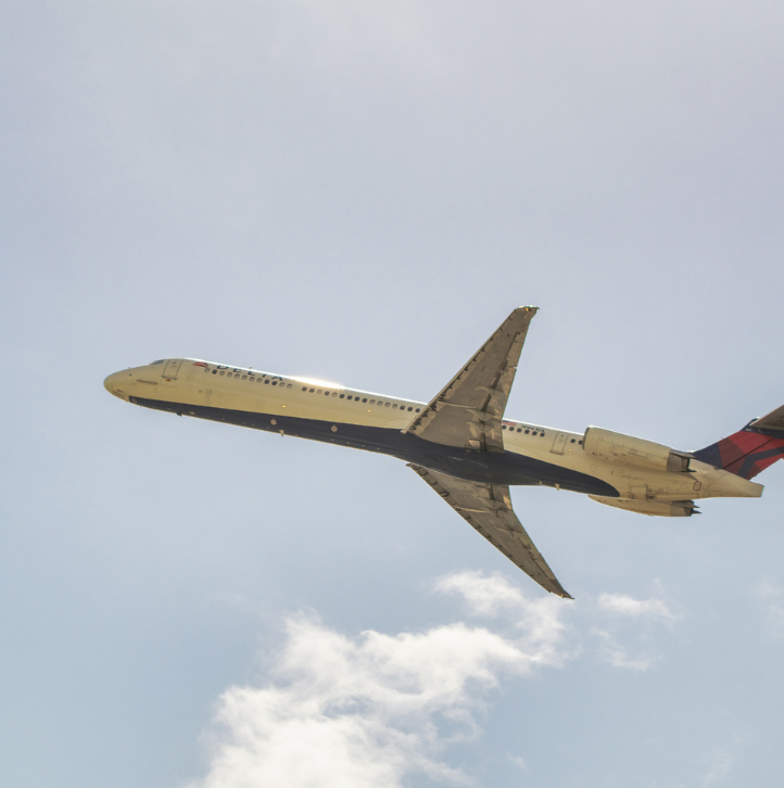 Commercial airplane flying through blue sky with white clouds
