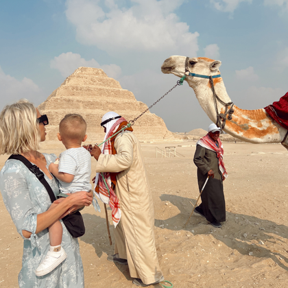 Family meeting camel at Egyptian pyramids in Cairo with tour guide