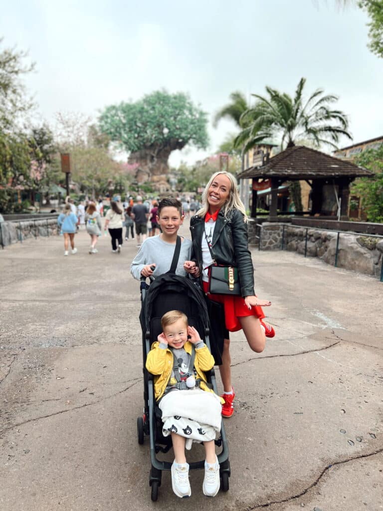A happy family with two children in a stroller enjoying a day at a theme park, illustrating the importance of keeping track of travel plans.