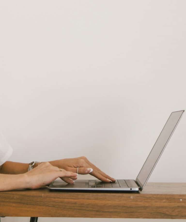 Close-up of a travel expert's hands while working on a laptop, emphasizing personalized coaching and strategic planning.