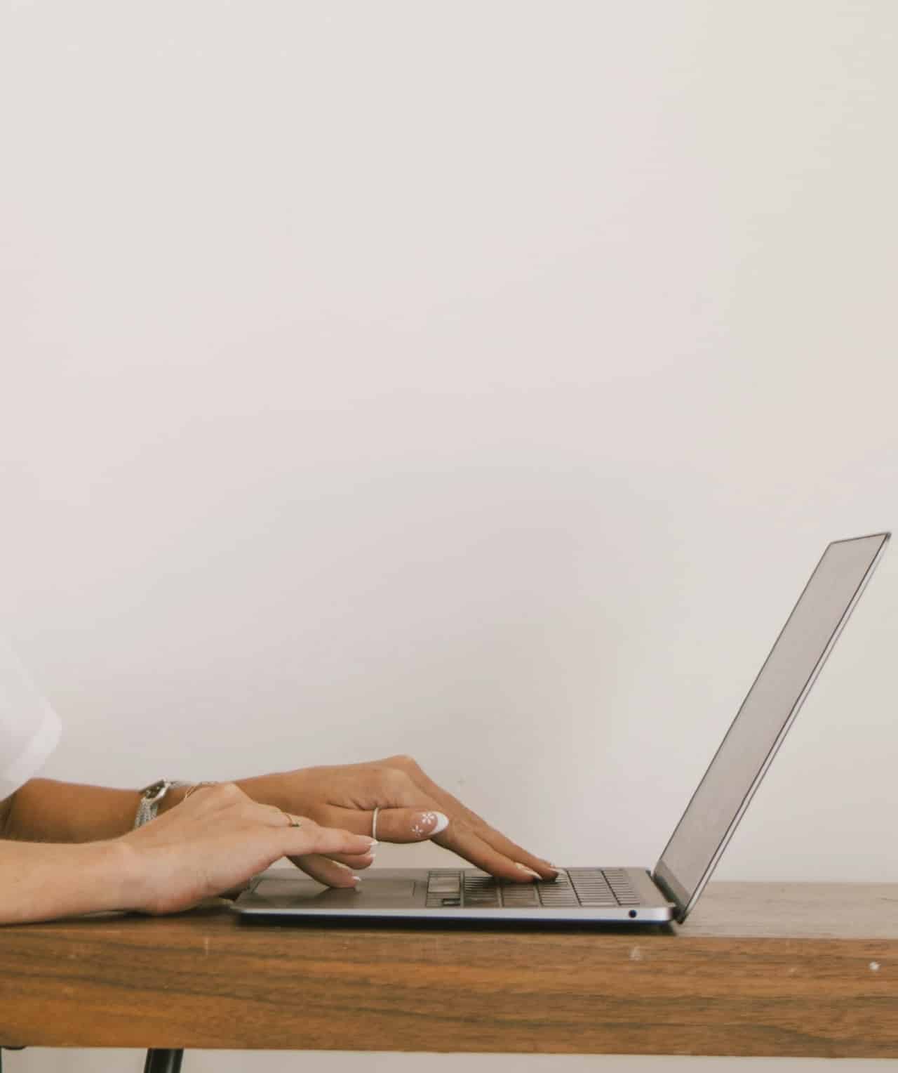 Close-up of a travel expert's hands while working on a laptop, emphasizing personalized coaching and strategic planning.